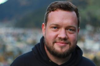 portrait of testa from the label duzzdownsan and the band von seiten der gemeinde, smiling, looking straight into the camera, he has beard and blue eyes